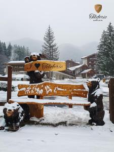 two statues of bears on a bench in the snow at Teleferic Grand Hotel in Poiana Brasov