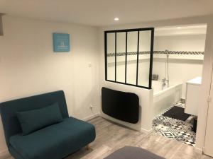 un salon avec une chaise bleue et une télévision dans l'établissement Jardin de la Béchade, à Bordeaux 2 autres photos