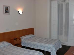 Habitación con 2 camas y ventana en Hostal Alonso, en Madrid