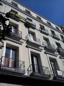 - un grand bâtiment blanc avec balcon et panneau dans l'établissement Hostal Alonso, à Madrid