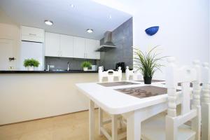cocina blanca con mesa blanca y sillas en Apartment MAKAI, en Estepona
