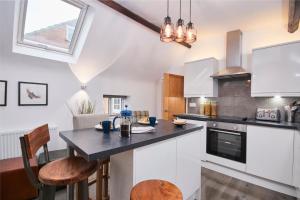 a kitchen with white cabinets and a black counter top at The Nutcracker Suite in Kegworth