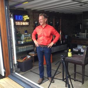 Un uomo con una camicia rossa davanti ad una telecamera di The Old Gin Distillery est 1850 a Londra