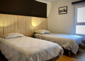 a bedroom with two beds and a window at "Le petit Moulinsard" in Bernay