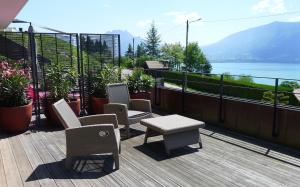 a deck with chairs and a table and a view of the water at Le Clos Du Lac - location de chambres in Veyrier-du-Lac