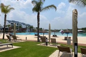 un complejo con piscina, sillas y palmeras en Penthouse 172 at The Blyde Crystal Lagoon en Pretoria