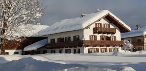 una casa cubierta de nieve con techo con nieve astillero cubierto en Ferienwohnungen Hanslbauer, en Krün