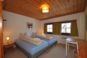 a bedroom with two beds and a table and two windows at Chasa Sager 2 in Scuol