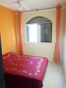 a bedroom with a red bed and a window at Capao da canoa Apto. 3 dorm in Capão da Canoa