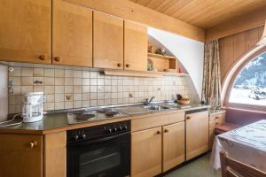 eine Küche mit Holzschränken, einer Spüle und einem Backofen in der Unterkunft Kleine Gartenwohnung Haus Forelle in Wolkenstein in Gröden