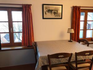 a dining room with a table and chairs and windows at Gîte L'Instant Durable in Oberbronn