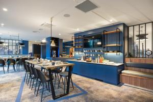 un restaurant avec des murs bleus, des tables et des chaises dans l'établissement Appart'City Collection Genève Aéroport - Ferney Voltaire, à Ferney-Voltaire