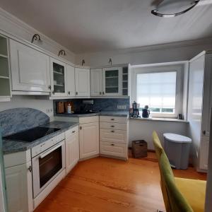 una cucina con mobili bianchi e pavimento in legno di Hanghaus der Villa Oderblick a Oderberg