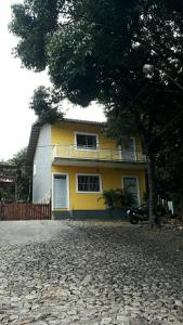 Una casa amarilla con un árbol delante. en Casa Neto&Lu en Guaramiranga