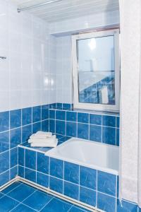 Baño de azulejos azules con bañera y espejo en Hotel Avallon, en Adler