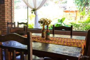 einen Tisch mit Blumen und zwei Flaschen darauf. in der Unterkunft Pousada e Restaurante Victórios in Caeté
