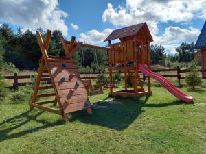 un parque infantil de madera con tobogán y estructura de juegos en Domek Letniskowy Całoroczny en Ciemno