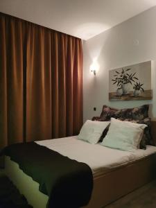 - une chambre avec un grand lit et des rideaux bruns dans l'établissement Silver Mountain Luna CD05, à Poiana Brasov