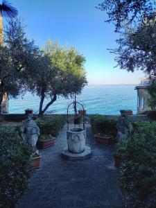 a stone walkway with a fountain in front of the ocean at Il Nido del Cigno in Sirmione
