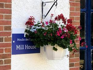 a flower pot hanging on a wall with a mill house sign at Moulin des Forges in Moutier-Malcard