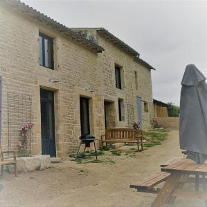 ein Backsteingebäude mit einem Grill und einem Picknicktisch in der Unterkunft Château des Loups - Les Cèdres Bleus in Échiré