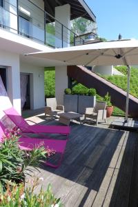 a patio with purple chairs and an umbrella at Le Clos Du Lac - location de chambres in Veyrier-du-Lac