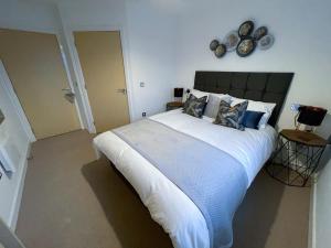 a bedroom with a large bed with white sheets and pillows at Station Side Penthouse in Wolverhampton
