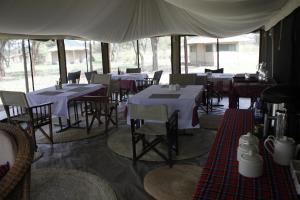 a restaurant with tables and chairs in a tent at Osero Serengeti Luxury Tented Camp in Banagi