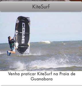 a man is on the water with a kite surfer at Pousada da Tina in Anchieta