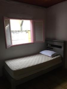 a bed in a room with a window at Casa da Dona Ilda in Pirenópolis