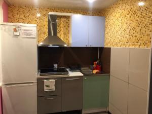 a small kitchen with a refrigerator and a stove at Apartments on pr. Lenina 7/42 in Monchegorsk