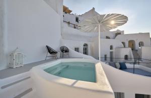 a white house with a hot tub on a balcony at Cave Suite Oia in Oia