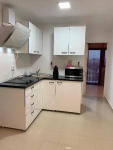 eine Küche mit weißen Schränken und einer schwarzen Arbeitsplatte in der Unterkunft Anastasia's Villa in Iaşi