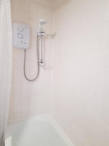 a white bathroom with a shower with a phone on the wall at Wonderland Guest House in Coventry