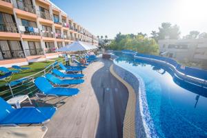 a swimming pool with blue lounge chairs and a resort at Avlida Hotel in Paphos