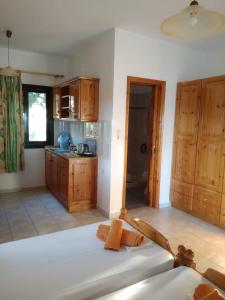 a room with a bed and a kitchen with wooden cabinets at Mabella Beach in Plati