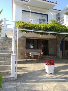 a house with a patio with a table and flowers at Mabella Beach in Plati