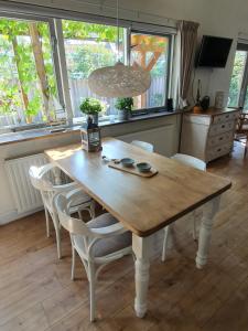 een houten tafel en stoelen in een kamer met ramen bij Woubrugge Logies in Woubrugge
