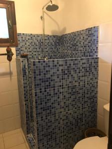a bathroom with a shower with a blue tiled wall at Hotel Praia Inhame Ecolodge in Porto Alegre