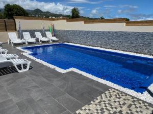 una piscina con sedie bianche e una piscina di Gîte Le Moringa a Saint-Pierre
