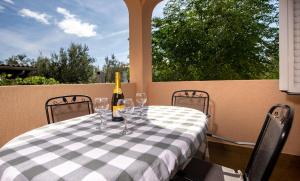 a table with a bottle of wine and glasses at Apartmani Milena in Rab