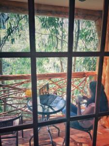 a woman sitting on a porch with a cup of coffee at Eco Quechua Lodge in Santa Teresa