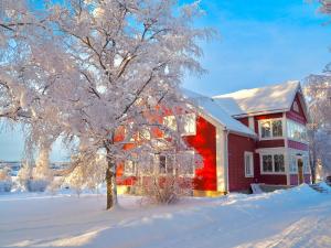 una casa roja con un árbol en la nieve en Sörbygården Bed & Breakfast, en Brunflo
