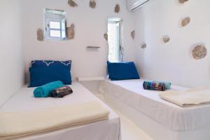 two beds in a white room with blue pillows at Villa Waves in Agios Ioannis Mykonos +47 photos