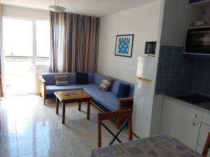 a living room with a blue couch and a table at Jandia Attico Vista Oceano in Morro del Jable