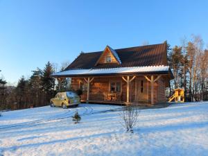 a log cabin with a car parked in the snow at Domek u Heli in Limanowa