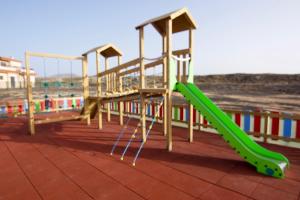 a playground with a green slide on the beach at The Blue Torrent, perfect for relaxing getaway in La Oliva