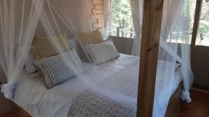 a bedroom with a canopy bed with white sheets and pillows at Mountain View Safari Lodge in Hoedspruit