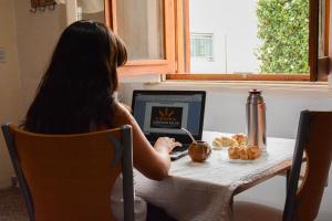 una mujer sentada en una mesa con un ordenador portátil en Complejo Solar Apart en Villa Regina