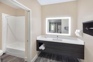 a bathroom with a sink and a toilet and a mirror at Super 8 by Wyndham Houston NW Beltway 8-West Rd in Houston +37 photos